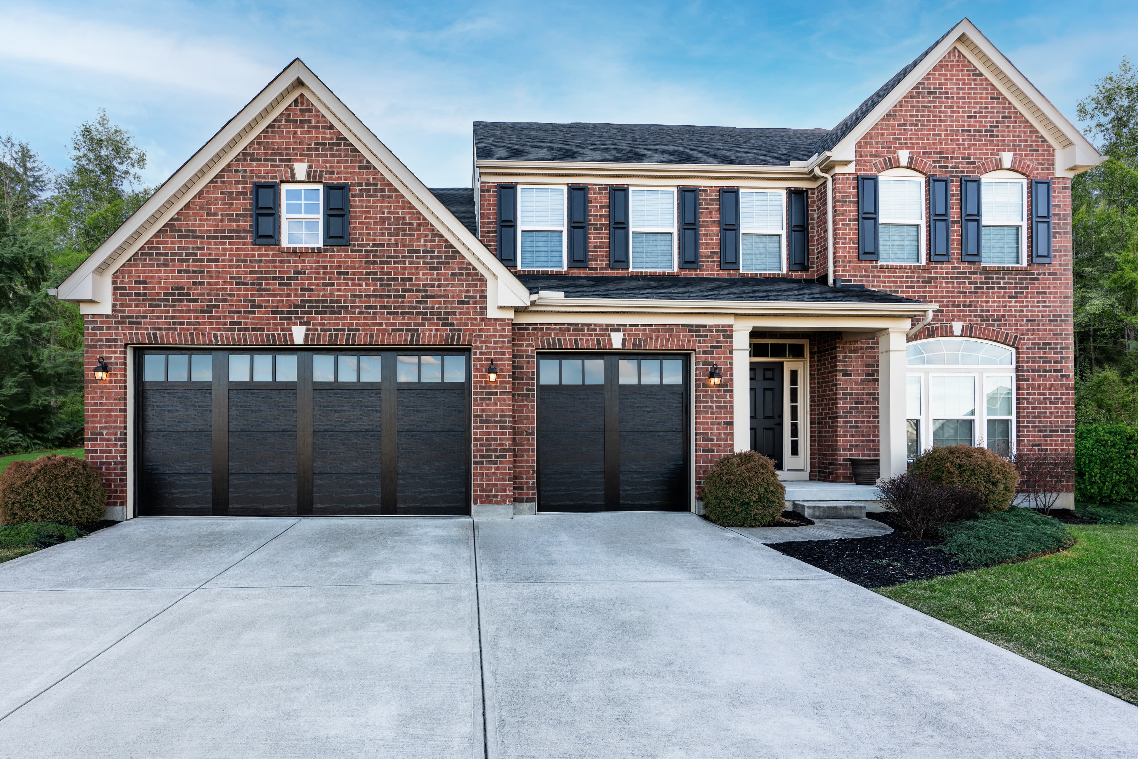 Brick colonial home with dark garage doors