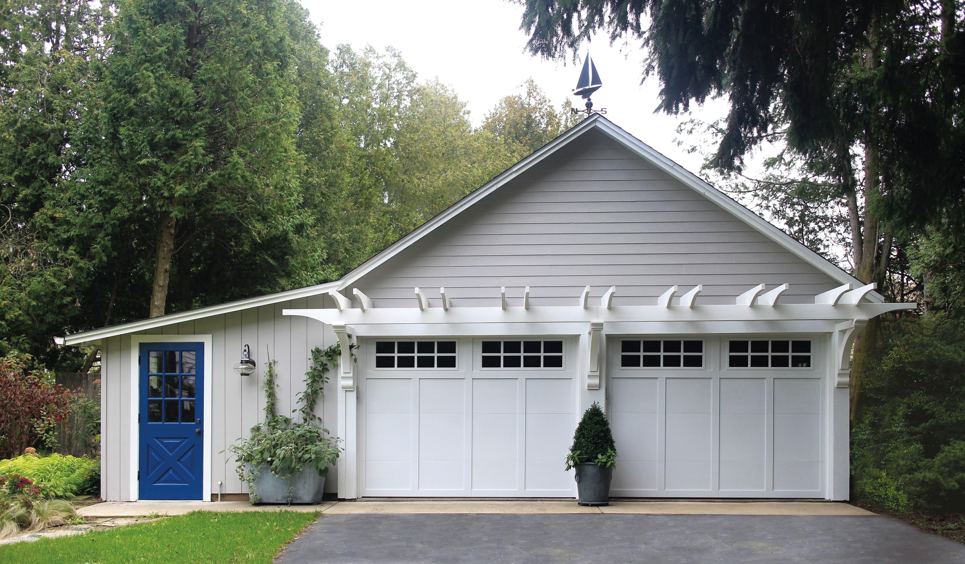 Well-maintained white cottage garage with greenery