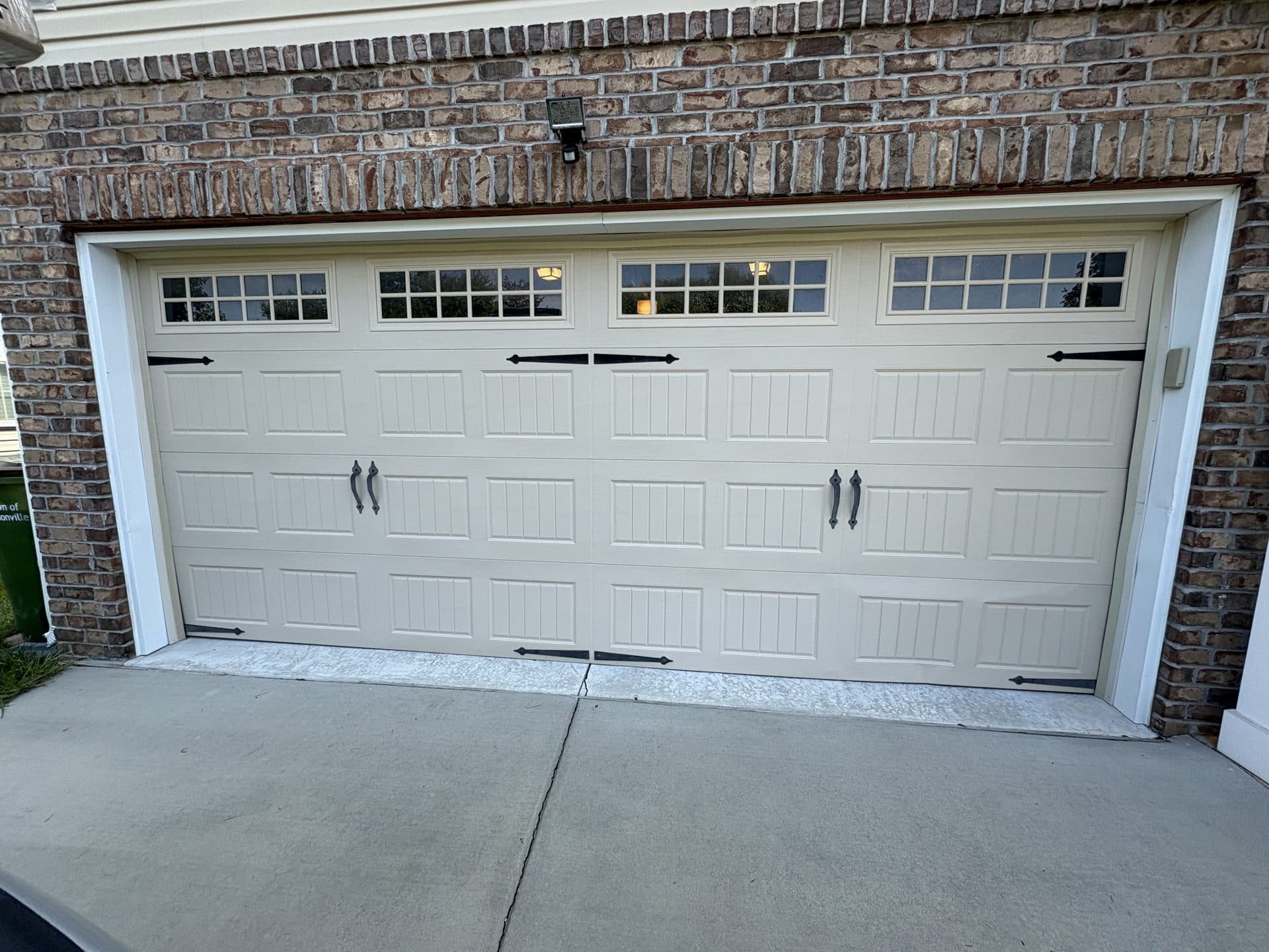 Carriage house garage door at golden hour with warm interior glow in Piedmont Triad NC
