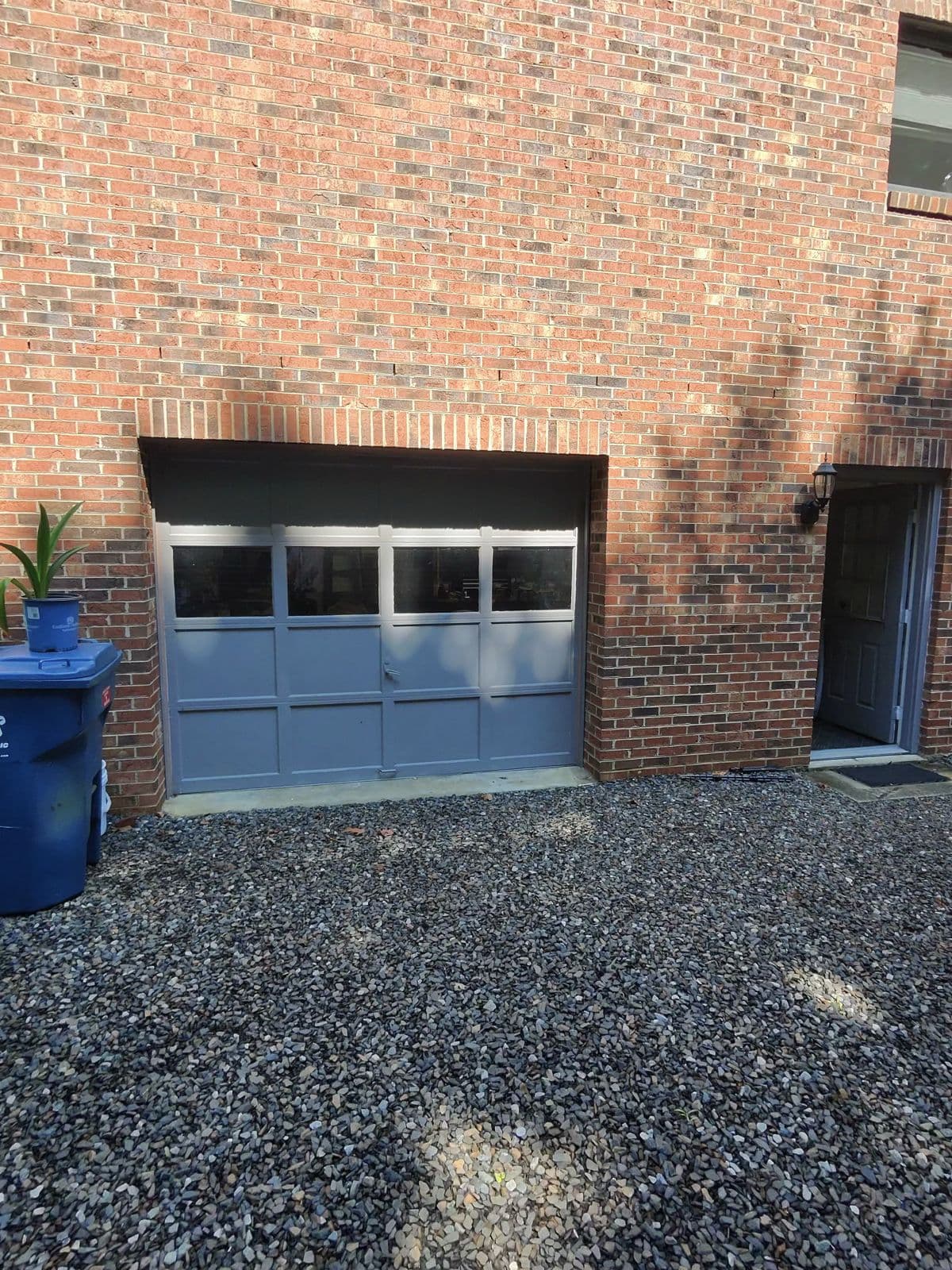 Wide view of dated blue-gray garage doors on two-bay brick home in Thomasville NC