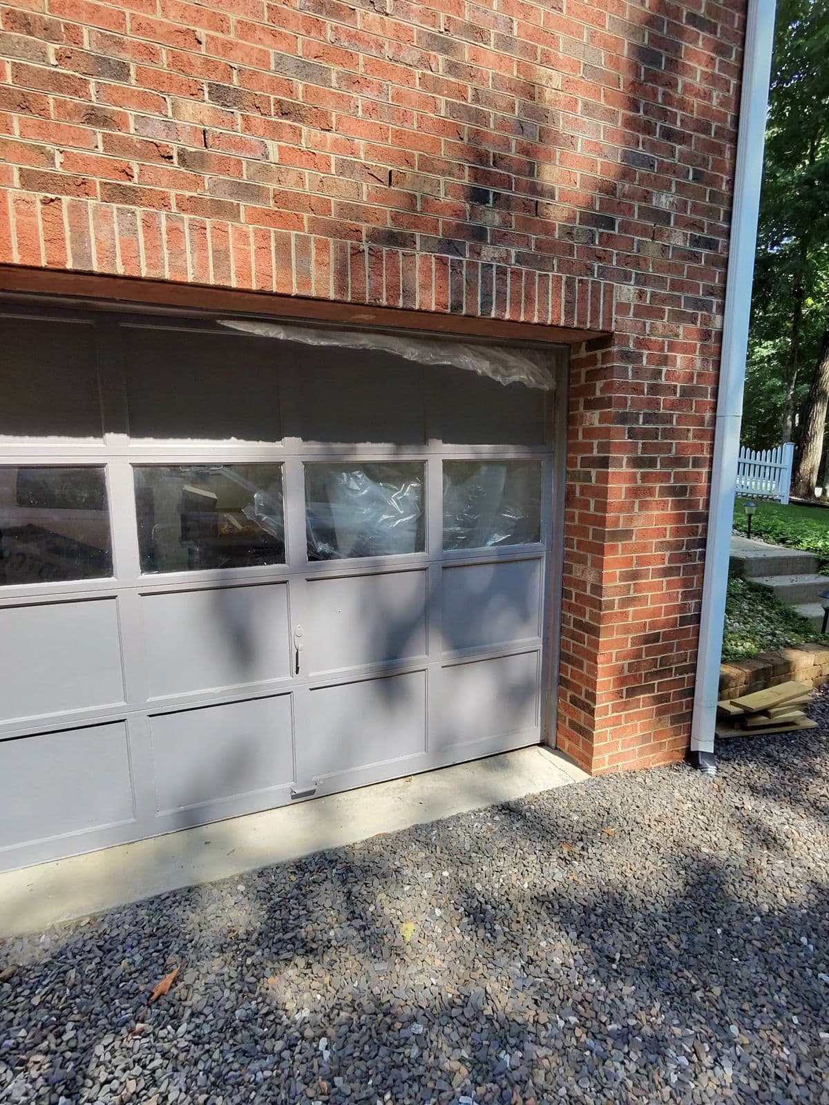 Faded blue-gray garage door on right bay of brick home before Clopay replacement in Thomasville NC