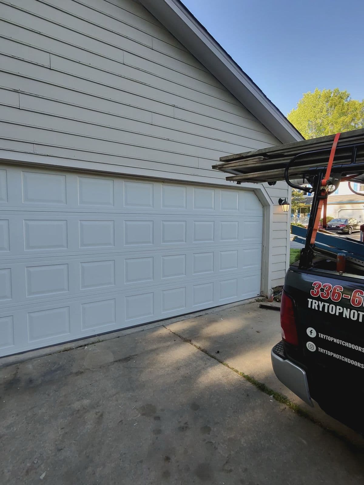 New white garage door installed with TNGD truck in driveway in Greensboro NC