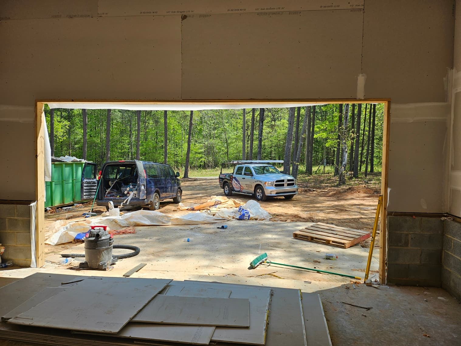 Interior of new construction garage bay before door installation with TNGD truck on wooded lot in Oxford NC