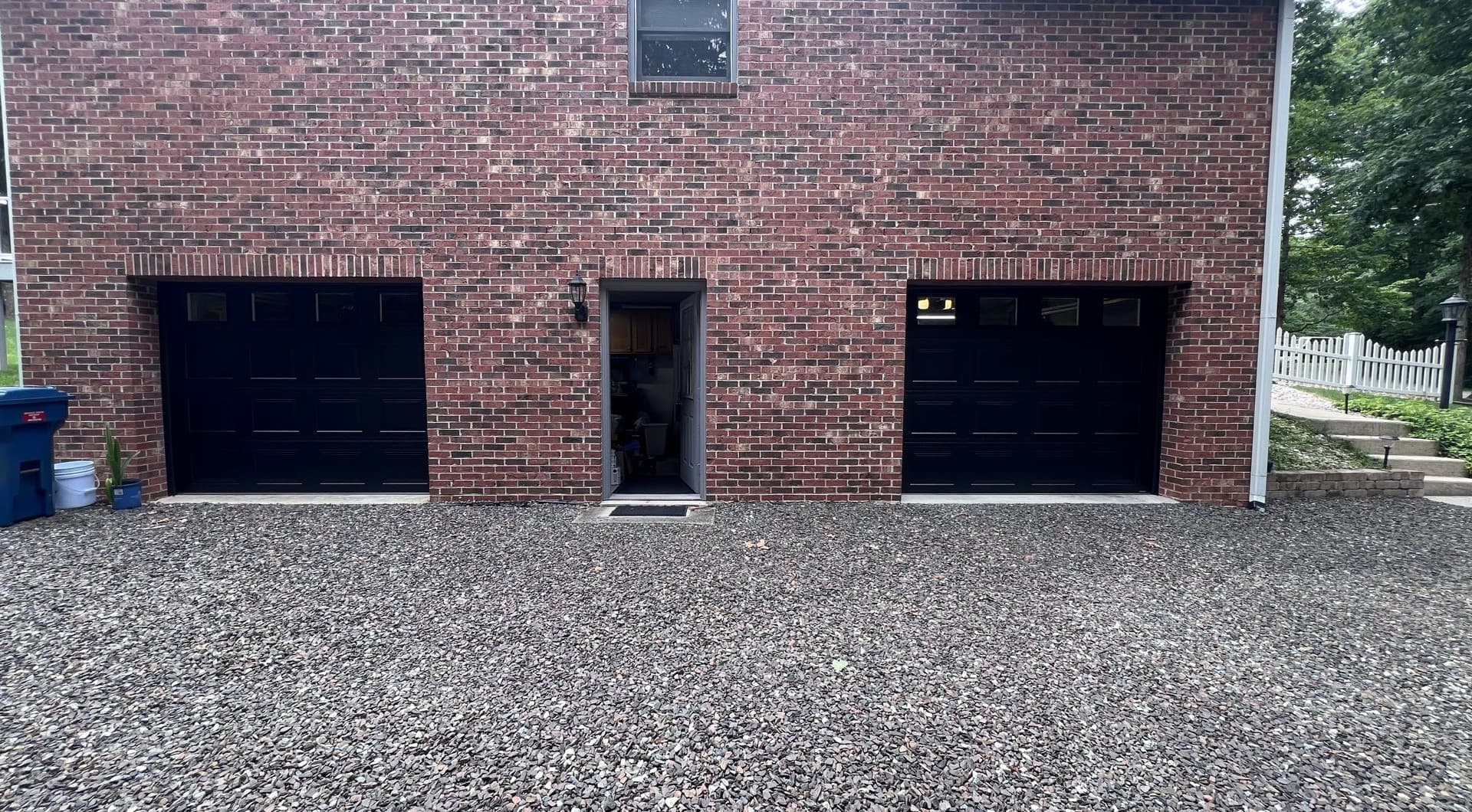 Two completed Clopay black raised-panel doors with transom windows on red brick home in Thomasville NC