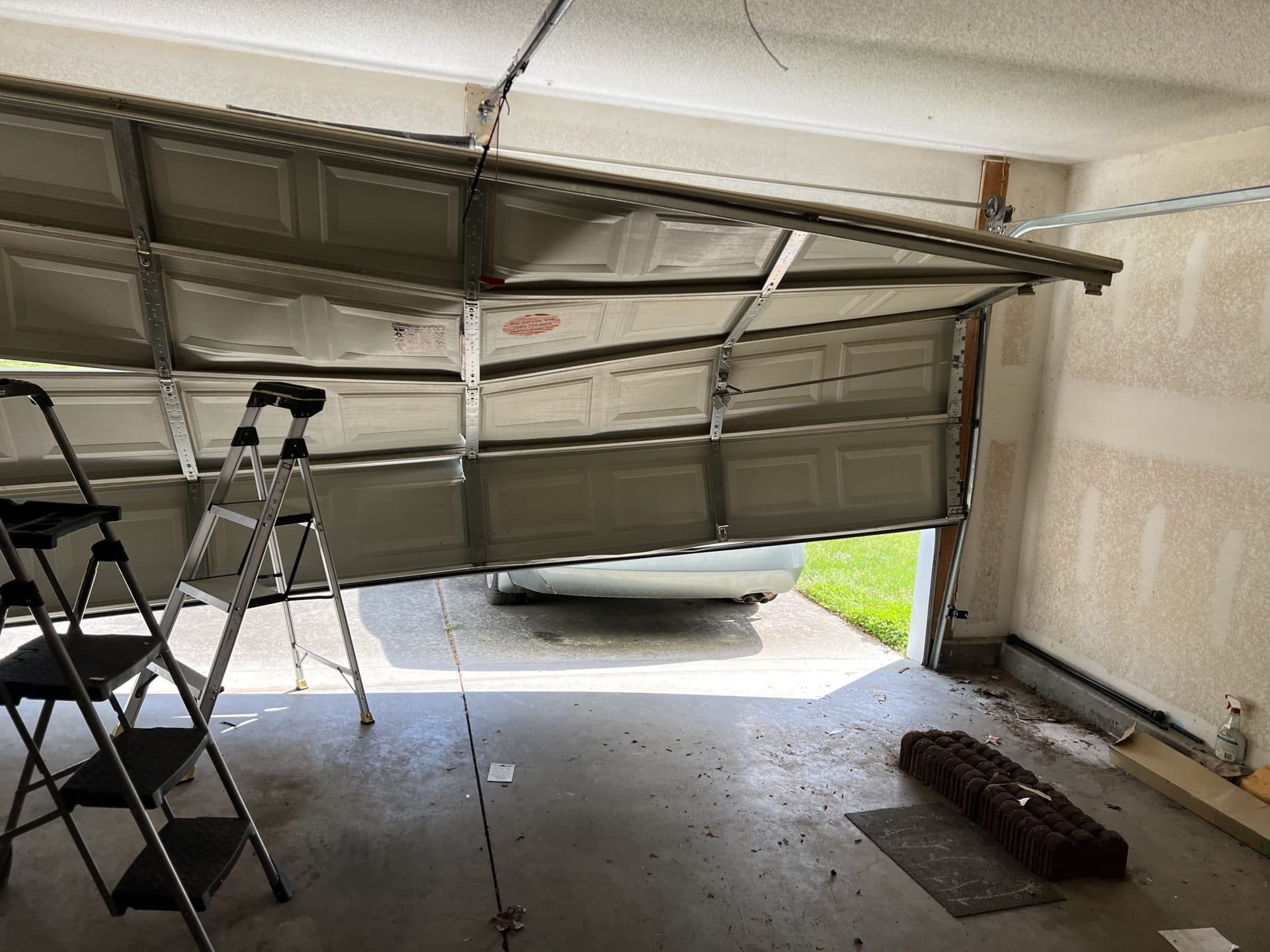Buckled garage door interior view showing mid-height damage in Whitsett NC